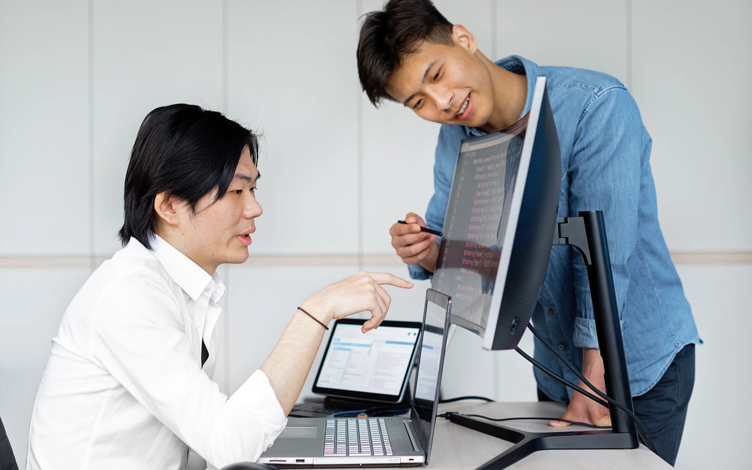 Two software engineers discussing code on a monitor at a shared desk